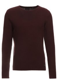 Bordeauxroter Strickpullover mit langen Ärmeln, rundem Ausschnitt, strukturiertem Stoff und einem kleinen Logoschild an der unteren Seite.