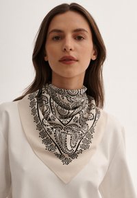 Kwadratowy szalik z czarnym wzorem paisley na beżowym tle, o gładkiej teksturze materiału i wykończonych brzegach.