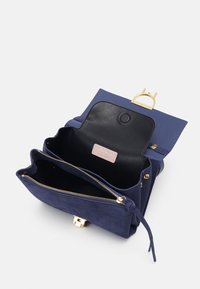 Borsa in suede blu navy con interno in pelle nera. Presenta una chiusura a scatto in tonalità oro e una chiusura con zip, con scomparti per l'organizzazione.