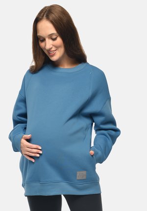 Felpa blu in cotone con maniche lunghe, scollatura rotonda e dettaglio della cerniera laterale. Presenta una patch con logo e una vestibilità ampia per il massimo comfort.