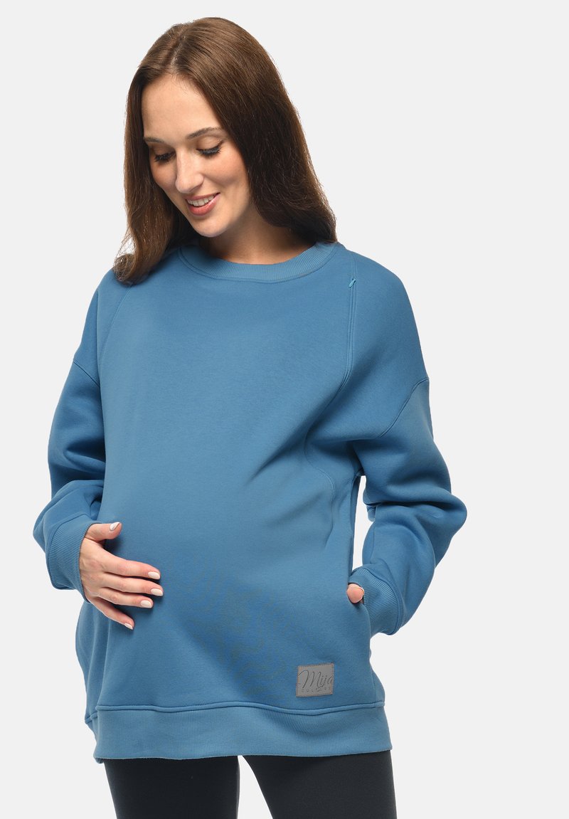 Felpa blu in cotone con maniche lunghe, scollatura rotonda e dettaglio della cerniera laterale. Presenta una patch con logo e una vestibilità ampia per il massimo comfort.