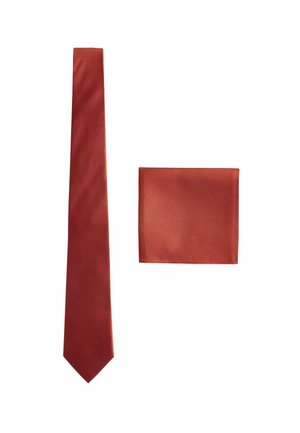 Cravate à motifs rouges avec une pochette assortie. Les deux présentent une finition texturée et un design géométrique. La cravate s'effile en une extrémité pointue.