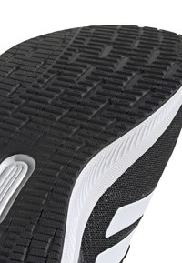 Black athletic shoe sole with textured rubber tread pattern; white accents along the edge and a distinct logo on the side.