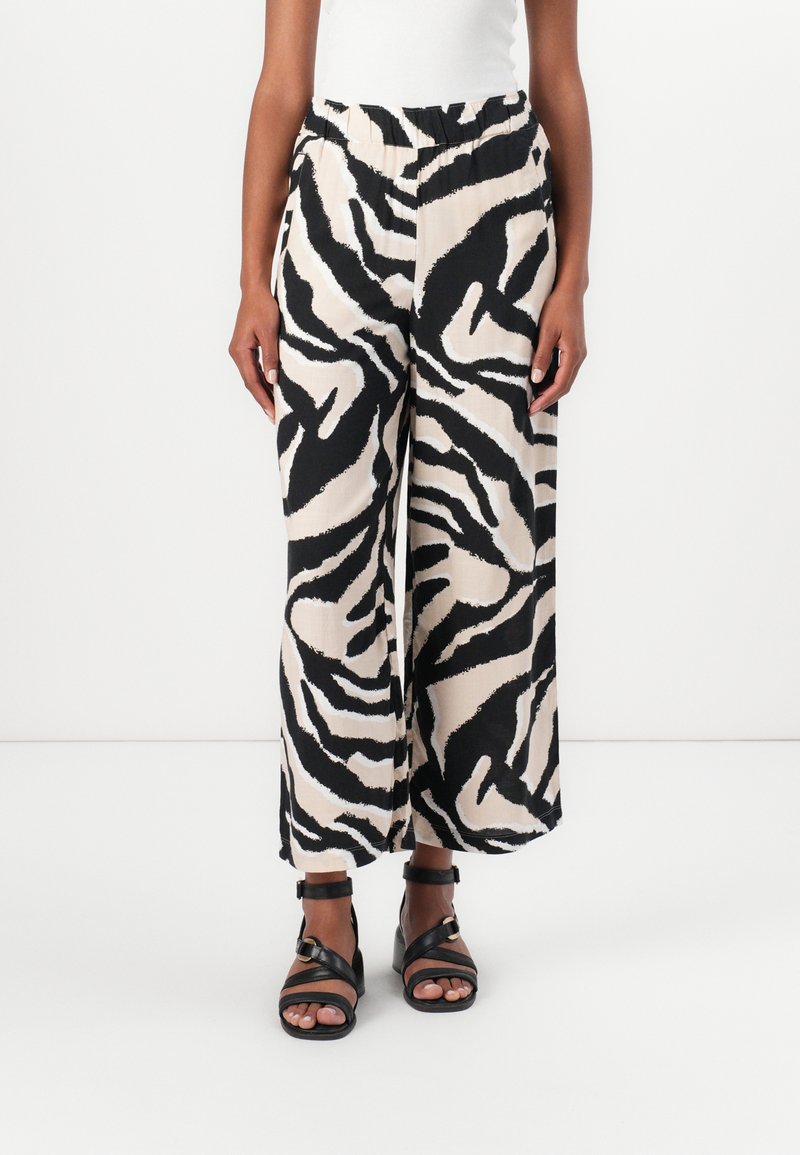 Pantalons larges avec un imprimé zèbre en noir et beige. Fabriqués en tissu léger, dotés d'une taille élastique et de deux poches latérales.