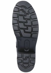 Black rubber outsole with a textured surface, featuring deep tread patterns for traction. Stamped brand identification on the heel.