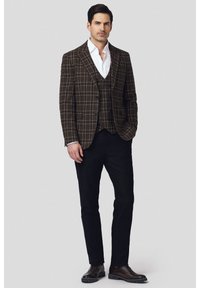 Brązowa, kratkowana marynarka zestawiona z dopasowanym kamizelką, białą koszulą i czarnymi spodniami. Brązowe buty dopełniają elegancki wygląd.