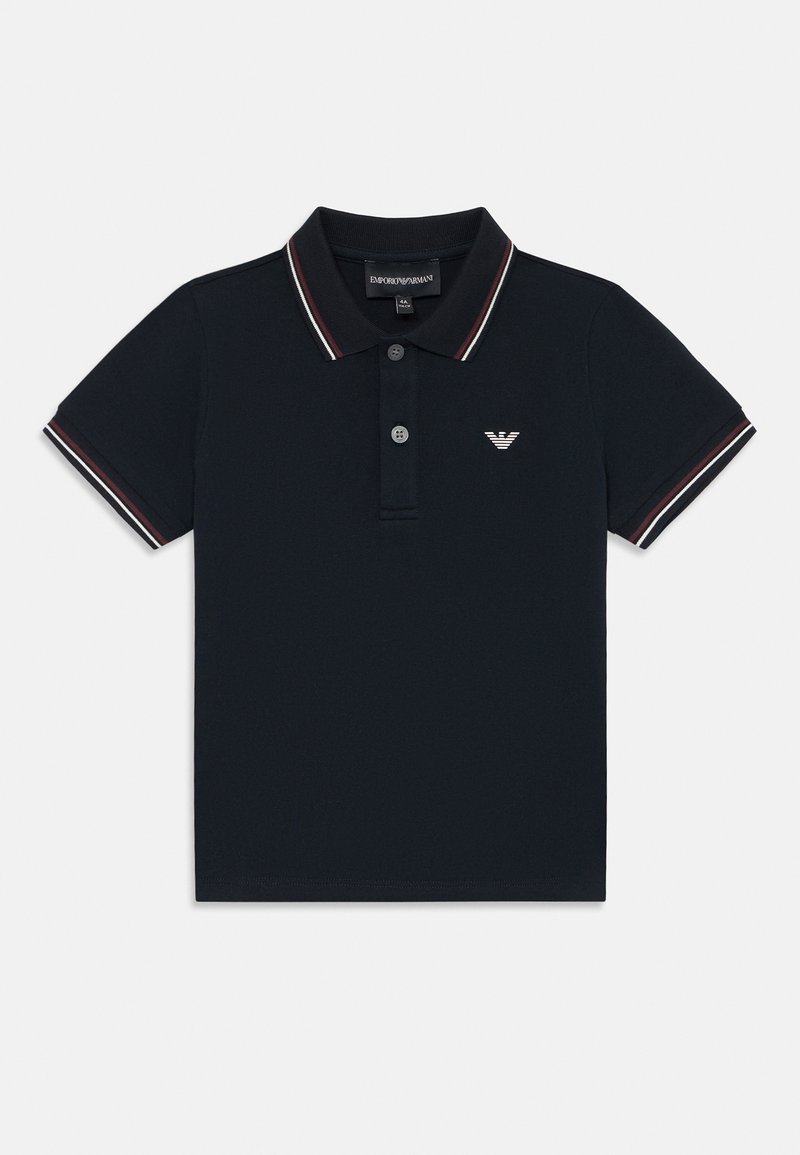 Temno modra polo majica iz bombaža, z zapenjanjem na tri gumbe, kontrastnimi rdečimi in belimi črtami na ovratniku in rokavih ter logotipom na prsih.