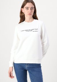 Felpa bianca con maniche lunghe, polsini e orlo a coste. Presenta scritte nere stampate sul fronte: “INDOSSO SOLO L'ULTIMO VESTITO È IL MIO LAVORO.”
