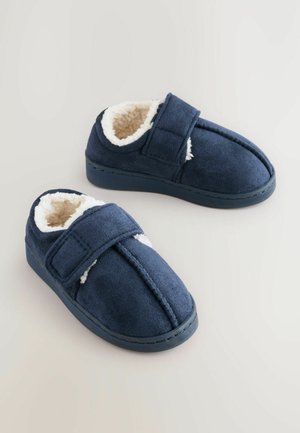 Marineblaue Hausschuhe aus weichem Wildleder mit einem flauschigen weißen Innenfutter, Klettverschluss und einem runden Zehendesign.