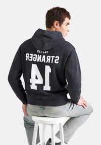 Tmavě šedá mikina s kapucí a šňůrkou, na zadní straně s bílým nápisem "REPLAY STRANGER 41". Hladký materiál a volný střih.
