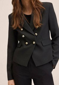 Sort dobbeltbrystet blazer med guldknapper, struktureret design, slå-om lapeller og sidelommer. Lavet af et glat materiale.
