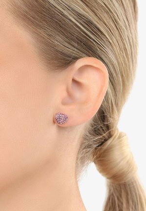 Herzförmige Steckerohrringe aus Roségold mit einem pinken Glitzer-Finish, das eine glatte Textur und eine sichere Metallrückseite aufweist.