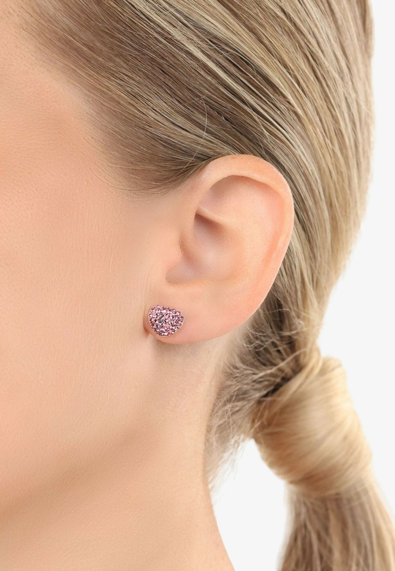 Orecchini a stud a forma di cuore in oro rosa, con una finitura glitter rosa, caratterizzati da una superficie liscia e un retro in metallo sicuro.