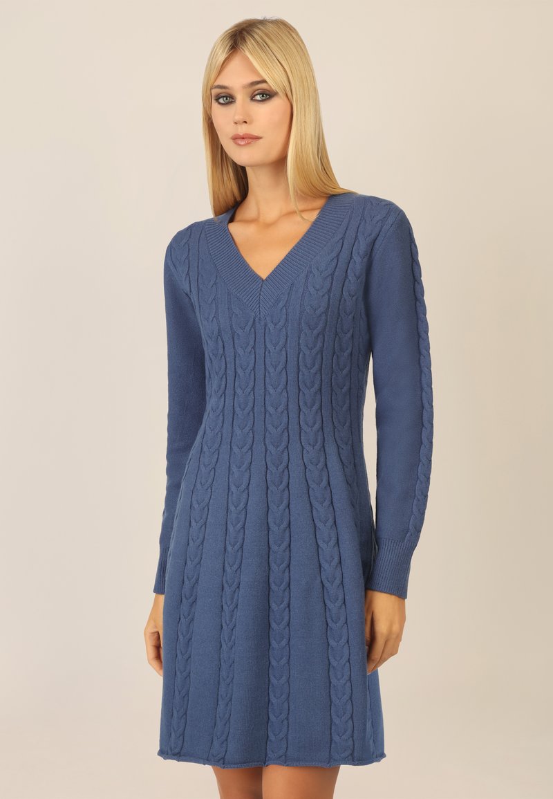 Abito blu lavorato a maglia con scollo a V, maniche lunghe e motivi a treccia in rilievo. Il tessuto è liscio con una texture morbida, che termina poco sopra le ginocchia.