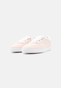 Ζευγάρι ανοιχτόροζ χαμηλά αθλητικά παπούτσια με λευκά κορδόνια και σόλες, με λεπτό πλευρικό λογότυπο και μινιμαλιστικό σχεδιασμό σε λευκό φόντο.