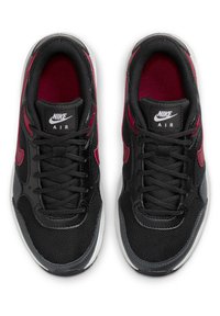 Chaussures de sport noires en matériau en maille et en cuir. Présentent des accents rouges et des détails gris. Les lacets et la languette de marque complètent le design.