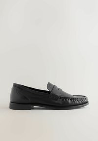 Black leather moccasin shoe with stitched detailing, a flat sole, and a strap across the vamp. Smooth texture and traditional loafer design.