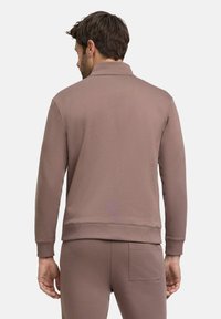 Pull en tissu mauve poussiéreux doux, avec un col haut et des poignets côtelés. Dispose d'une poche arrière sur le pantalon assorti.