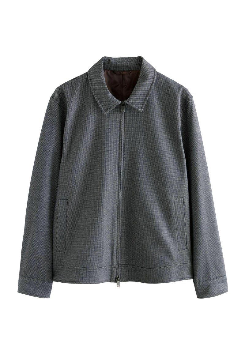 Chaqueta gris con cremallera y cuello, de tejido texturizado, con dos bolsillos laterales y un forro interior suave. Diseño limpio y sencillo.
