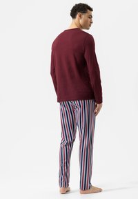 Langarm bordeaux top gecombineerd met gestreepte broek in marineblauw, rood en wit. Lichtgewicht stof, casual pasvorm en smal broekontwerp.