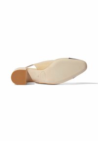 Scarpa piatta in pelle beige con punta a punta e tacco quadrato basso. La suola è liscia con dettagli di branding impressi.