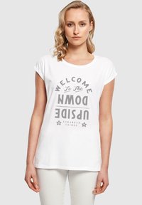Hvid bomulds-T-shirt med et gråt grafisk print, der står "WELCOME TO THE UPSIDE DOWN", med oprullede ærmer og en afslappet pasform.
