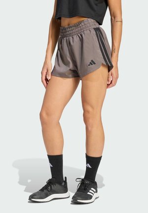 Gray athletic shorts with a stretchy, elastic waistband and black side stripes, paired with black shoes and socks.