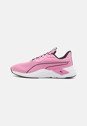 Zapatilla deportiva de corte bajo en color rosa con forro interior negro, suela blanca, logo de Puma negro y acentos laterales en rosa sobre un fondo blanco.