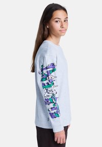Lichtgrijze langemouwen T-shirt van katoen, met kleurrijke grafische ontwerpen in paars en groen op de linker mouw.