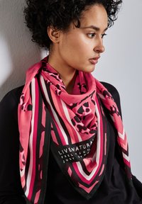 Rosa sidenhalsduk med geometriska ränder och accenter i leopardmönster, med en svart kant och tryckt text på botten.