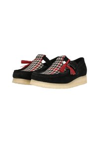 Suède loafers met een zwart-rood houndstooth stofaccent, voorzien van franjes en een solide crème kleurige zool.