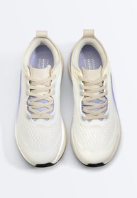 Paire de chaussures de course beige clair et lavande avec lacets, tige en mesh respirant et semelles épaisses amortissantes vue de dessus.