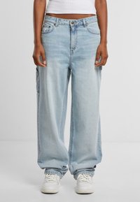 Ljusblå, vida jeans i denim. Har stora sidofickor och en klassisk femfickorsdesign med knäppning.