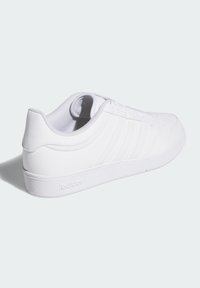 White sneaker featuring a smooth synthetic upper, textured accents, round toe, low profile, and a logo on the heel. Laces for closure.