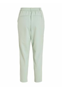 Pantalons vert clair avec taille élastique, design de jambe fuselée, poches arrière et texture de tissu lisse.