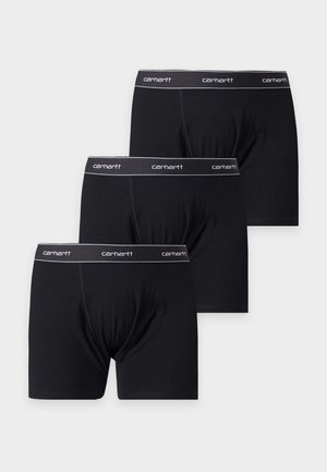 Τρία μαύρα εσώρουχα boxer Carhartt με λογότυπο στο ελαστικό λάστιχο της μέσης στοιβαγμένα σε λευκό φόντο.