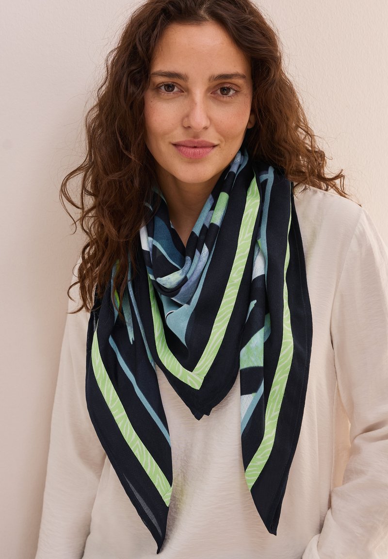 Sciarpa triangolare multicolore in navy, verde e blu con motivi geometrici e una texture leggera e morbida, drappeggiata attorno al collo.