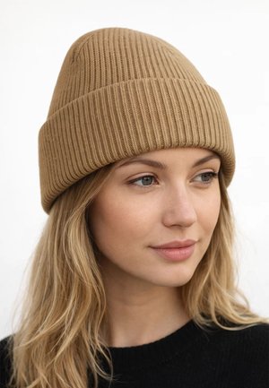 Young woman with long blond hair wearing a tan ribbed knit beanie and black sweater, looking slightly to the right.