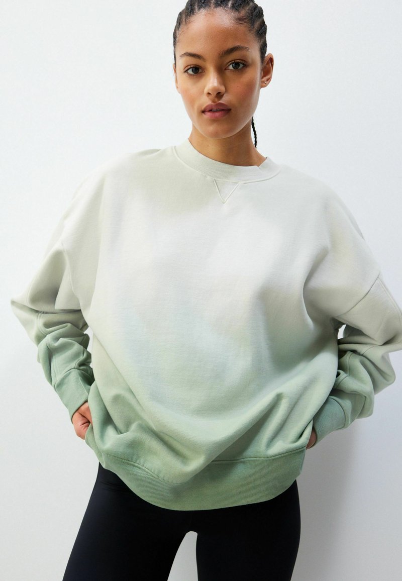 Sweatshirt verde deschis cu gradient, cu guler rotund, croială oversized și manșete striate. Textură netedă și tranziție de culoare subtilă.
