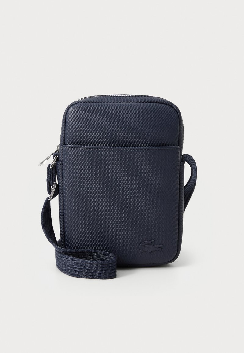 Geantă bleumarin tip crossbody dintr-un material texturat, cu închidere cu fermoar, curea ajustabilă și logo embossat pe față.