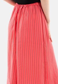 Falda plisada rosa con rayas negras verticales, cintura elástica, tela ligera, cae hasta el tobillo, textura suave, ajuste casual.