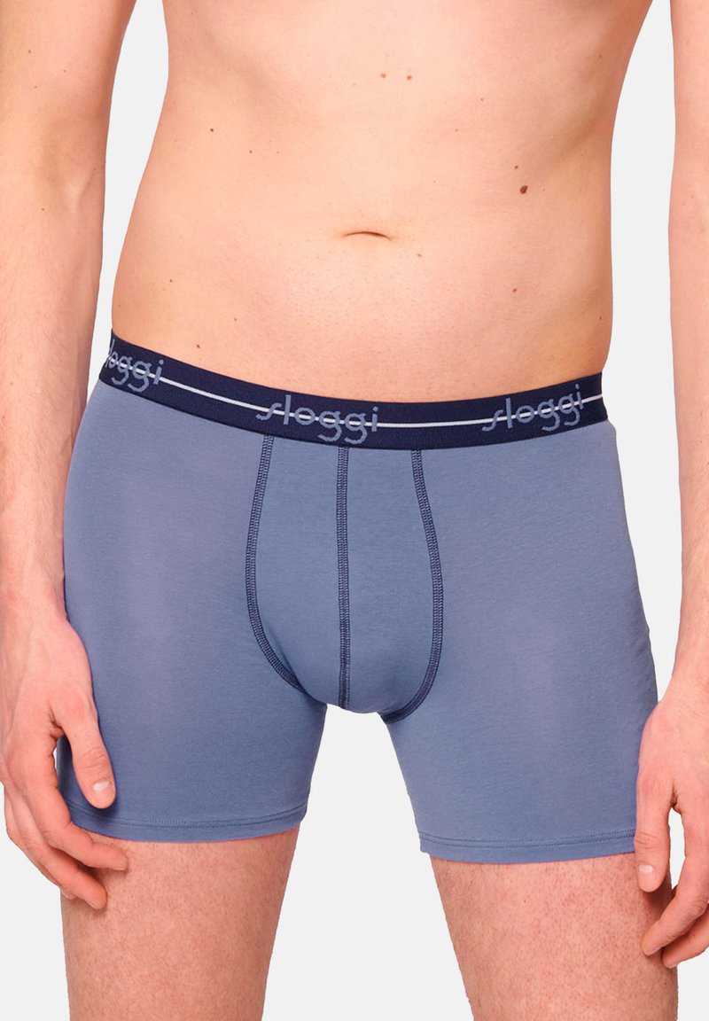 Mäns blå bomullboxer i brief-stil med midjeband i marinblått som har "sloggi"-logotyp, slät textur och figurnära design.