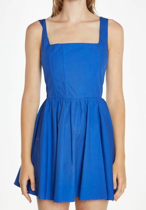 Femme portant une robe sans manches bleu vif cintrée, avec un col carré et une jupe froncée et évasée.