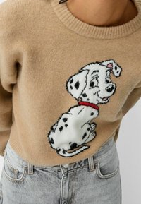 Beige gestrickter Pullover mit einem Dalmatiner-Hundedesign in Schwarz und Weiß mit roter Halsband, rundem Ausschnitt und weicher Textur.