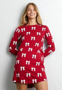 Punainen pitkänäkkinen mekko, jossa on toistuva valkoinen nauhakuosi. Valmistettu pehmeästä kankaasta, joka on rento ja mukava leikkaukseltaan, sekä kaareva helma.