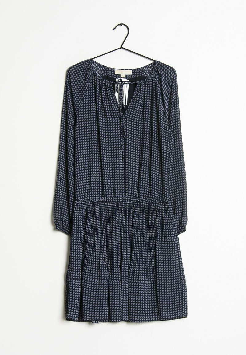 Robe bleu marine à manches longues avec petit motif de pois blancs, taille froncée et encolure goutte d'eau avec lien sur un cintre noir sur fond blanc.