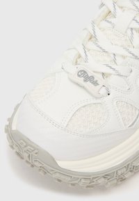 Bijela tenisica s gornjom od mrežaste tkanine, teksturiranim detaljima i gumeni potplat s istaknutim profilom. Na vezicama je vidljiva oznaka "Buffalo".