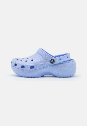 Sabot violet clair pailleté avec des trous de ventilation, une sangle au talon et une semelle texturée antidérapante.