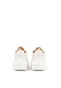 Baskets blanches avec une semelle en caoutchouc texturée, une tige en cuir lisse et des accents marron. Dotées d'une anse à l'arrière et d'une étiquette de talon à logo.