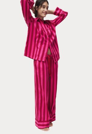 Conjunto de pijama a rayas rosas que incluye una camisa de botones con bolsillo, pantalones holgados con cinturilla ajustable y una textura suave.